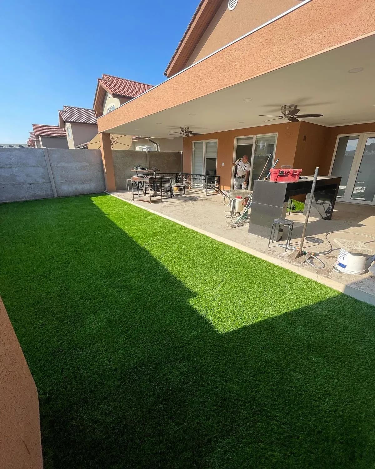Pasto sintético instalado frente a una terraza cubierta, con la obra aún en curso